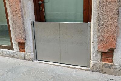 A wooden front door with solid metal barrier in front of it to prevent water getting under the door