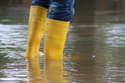 Person wearing jeans and yellow wellies standing in shallow floodwater