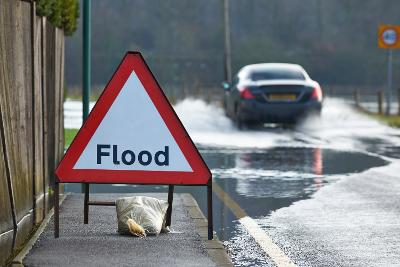 Flood warning sign on the pavement next to a flooded road