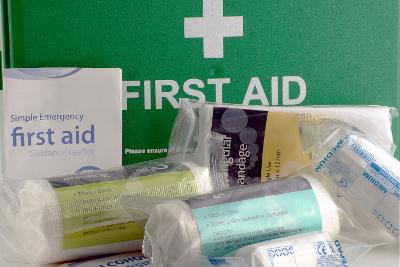 Sterile bandages and dressings in front of a green first aid box.