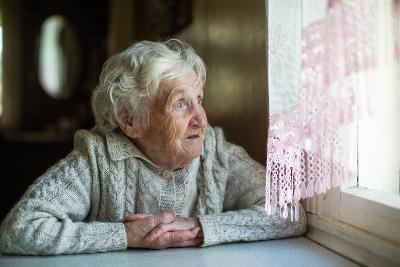 Elderly woman sitting at a table looking out of a window